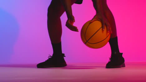 Nahaufnahme-Eines-Studioporträts-Eines-Männlichen-Basketballspielers,-Der-Den-Ball-Vor-Rosa-Beleuchtetem-Hintergrund-Dribbelt-Und-Hüpft-8